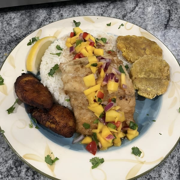 El Gordo Coqui's Spanish dish with fish, mango salsa, rice, fried plantains, and a lemon wedge.
