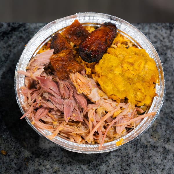 El Gordo Coqui's Spanish dish with shredded pork, rice, fried plantains, and sweet plantains in a foil container.